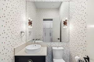 Half bathroom with vanity and wallpapered walls