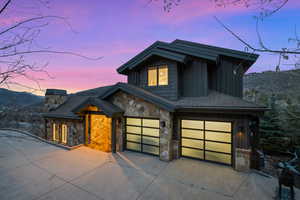 Contemporary house featuring board and batten siding, concrete driveway, stone siding, and an attached garage