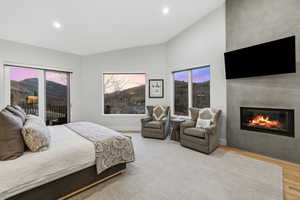 Bedroom featuring access to exterior, light wood finished floors, a fireplace, recessed lighting, and vaulted ceiling