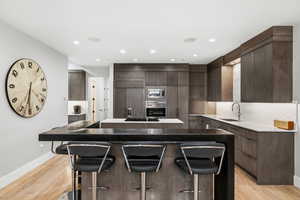 Kitchen with a kitchen island, a kitchen bar, light wood-style floors, modern cabinets, and recessed lighting
