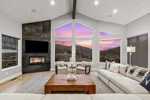 Living room featuring a high wood beamed ceiling, a multi sided fireplace, and light wood finished floors