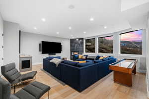 Living room featuring light wood-type flooring, recessed lighting, and a warm lit fireplace
