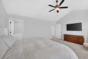 Bedroom with light colored carpet, ceiling fan, and a high ceiling