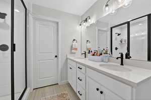 Full bath featuring a stall shower, double vanity, and a textured ceiling