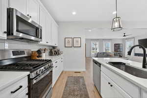Kitchen with stainless steel appliances, white cabinets, and light stone counters