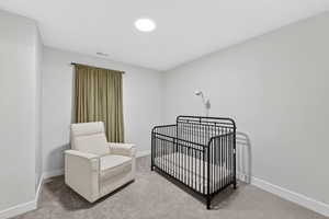 Bedroom featuring light carpet and a crib