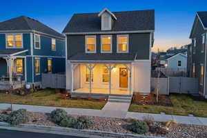 Traditional-style home featuring a gate, a porch, a front yard, and roof with shingles