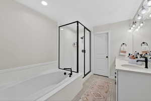 Full bath with double vanity, a garden tub, and a stall shower