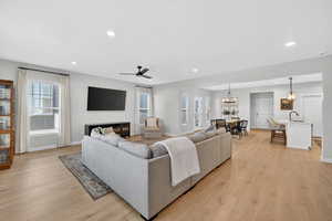 Living room featuring ceiling fan, light wood-style floors, and a chandelier
