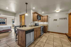Kitchen featuring a peninsula, a breakfast bar, stainless steel appliances, decorative light fixtures, and open floor plan
