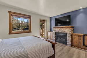Bedroom with wood finished floors and a stone fireplace