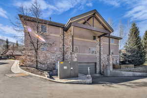 View of front facade featuring stone siding, stucco siding, and a garage