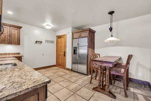 Kitchen with stainless steel built in refrigerator, light stone countertops, and hanging light fixtures