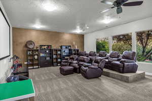 Home theater with a ceiling fan, carpet flooring, and a textured ceiling