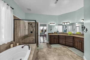 Full bathroom featuring double vanity, a stall shower, a whirlpool tub, and ensuite bath