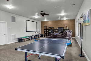 Rec room with ceiling fan, a textured ceiling, and carpet