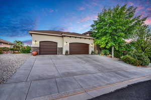 Mediterranean / spanish house with stucco siding, an attached garage, stone siding, and driveway