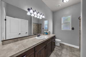 Bathroom featuring vanity, a shower, and a textured ceiling