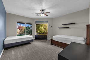 Carpeted bedroom with a ceiling fan and a textured ceiling