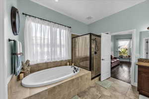 Full bath featuring ensuite bathroom, a stall shower, vanity, and a garden tub