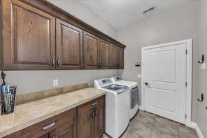 Laundry area with cabinet space, washer and dryer, and a textured ceiling