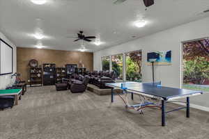Rec room with ceiling fan, carpet floors, and a textured ceiling