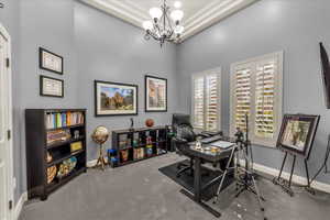 Carpeted office featuring suspended lighting and a high ceiling