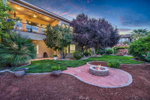 View of green lawn with a patio, a fire pit, and a balcony