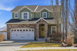Craftsman inspired home with roof with shingles, concrete driveway, a garage, stone siding, and a front yard