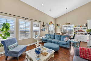 Living area featuring dark wood-type flooring, vaulted ceiling, and recessed lighting