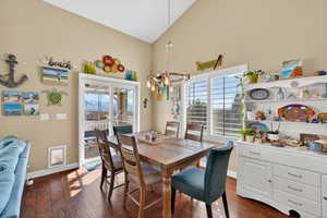 Dining space with dark wood-style floors, vaulted ceiling, and plenty of natural light
