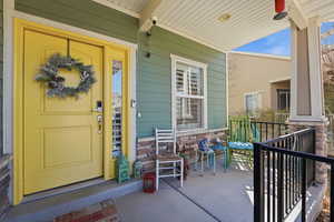 Doorway to property with stone siding and covered porch