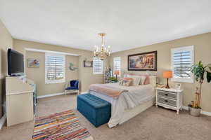 Bedroom with suspended lighting and light carpet