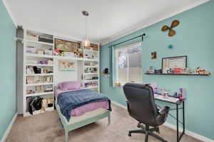Bedroom featuring light colored carpet, an office area, and ornamental molding