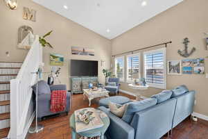 Living room featuring dark wood-type flooring, lofted ceiling, and recessed lighting