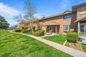 View of front of home featuring a front yard, a chimney, brick siding, and a porch