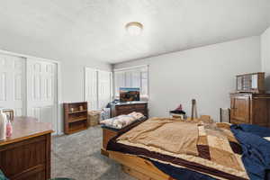 Bedroom featuring two closets, a textured ceiling, and carpet floors