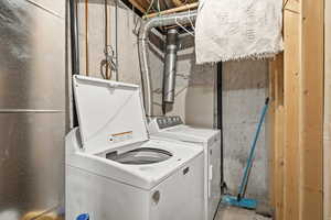 Laundry area featuring concrete flooring and washing machine and clothes dryer