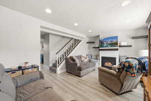 Living room with a glass covered fireplace, light wood finished floors, recessed lighting, and a textured ceiling