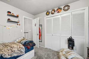 Bedroom featuring carpet, a closet, and a textured ceiling