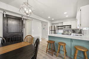 Kitchen featuring a barn door, a kitchen bar, stainless steel appliances, open shelves, and a peninsula