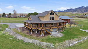 Back of house with roof with shingles, a mountain view, a view of countryside, and a large porch