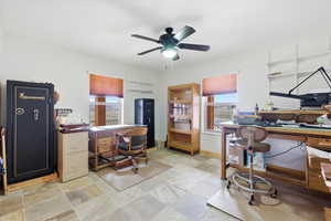Home office featuring ceiling fan and light stone finish floors