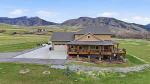 Farmhouse-style home featuring driveway, a mountain view, a view of countryside, a garage, and roof with shingles