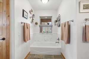 Full bath featuring a garden tub and baseboards