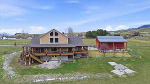 Back of property featuring an outbuilding, a yard, a deck with mountain view, and a view of rural / pastoral area