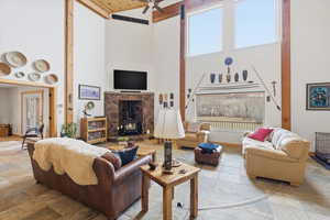 Living area featuring a wood stove, a high ceiling, ceiling fan, and healthy amount of natural light