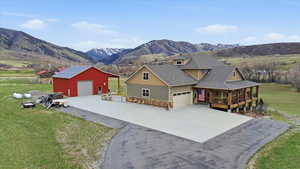 View of front facade with a front yard, an outbuilding, a mountain view, stone siding, and a detached garage