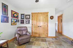 Living area featuring stone tile floors and ceiling fan