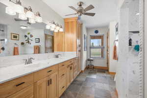 Full bathroom featuring double vanity, ceiling fan, and stone finish flooring